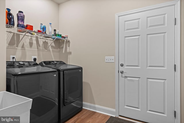 clothes washing area with wood-type flooring, separate washer and dryer, and sink