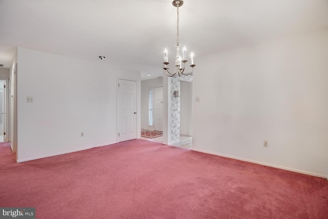 carpeted empty room with an inviting chandelier