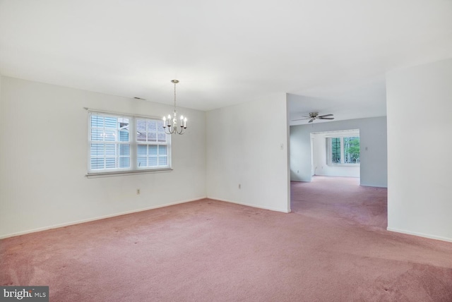 empty room with carpet, a healthy amount of sunlight, and ceiling fan with notable chandelier