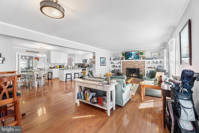 living room featuring a brick fireplace, light hardwood / wood-style flooring, and ornamental molding