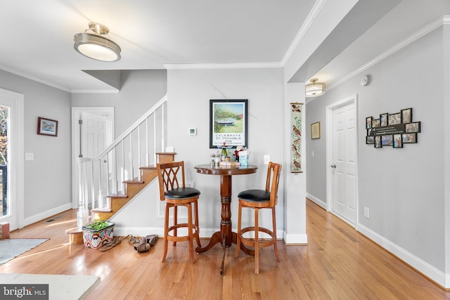 dining space with light hardwood / wood-style floors and ornamental molding