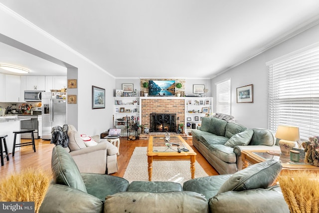 living room featuring crown molding, light hardwood / wood-style floors, and a brick fireplace