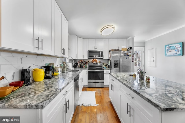 kitchen featuring white cabinetry, sink, stainless steel appliances, stone countertops, and light wood-type flooring