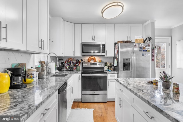 kitchen featuring light stone countertops, sink, stainless steel appliances, light hardwood / wood-style floors, and white cabinets