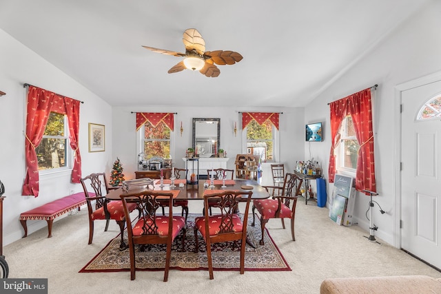 dining space with ceiling fan, plenty of natural light, light carpet, and lofted ceiling