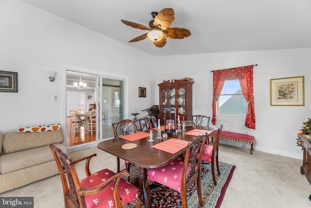 carpeted dining space with ceiling fan with notable chandelier and vaulted ceiling