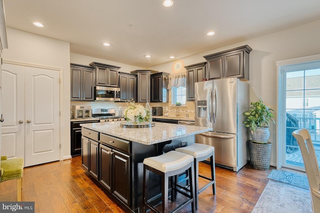 kitchen with decorative backsplash, appliances with stainless steel finishes, dark hardwood / wood-style flooring, a breakfast bar, and a kitchen island