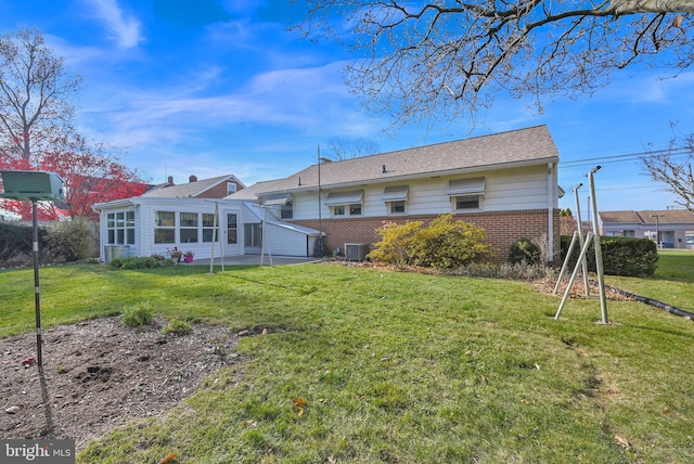 back of house featuring a lawn, a sunroom, and cooling unit