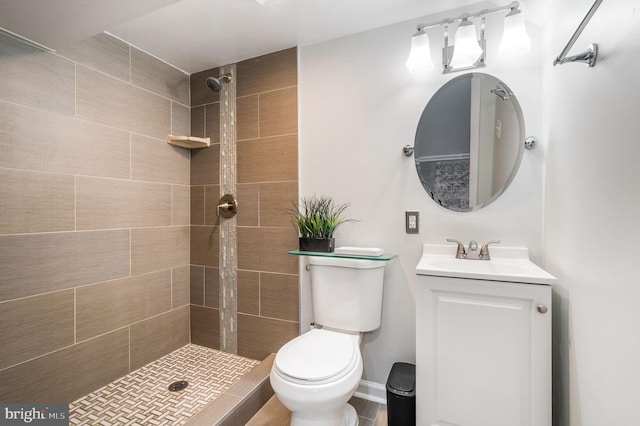 bathroom with a tile shower, vanity, and toilet