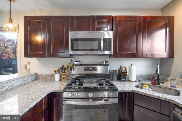 kitchen featuring light stone countertops, appliances with stainless steel finishes, hanging light fixtures, and sink