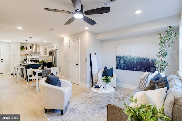 living room featuring ceiling fan and light hardwood / wood-style floors