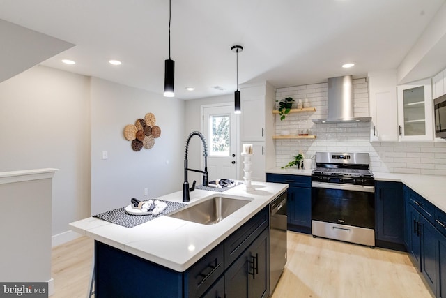 kitchen featuring white cabinets, wall chimney exhaust hood, stainless steel appliances, and blue cabinets