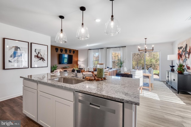 kitchen with white cabinets, sink, stainless steel dishwasher, light wood-type flooring, and a chandelier