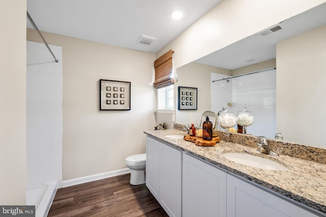 bathroom featuring wood-type flooring, vanity, a tile shower, and toilet