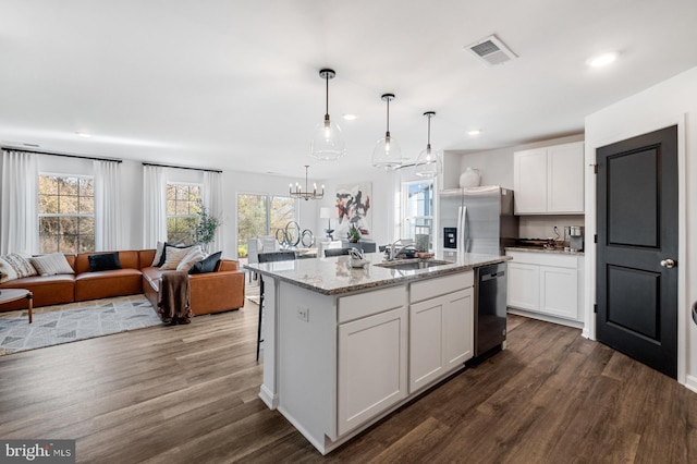 kitchen with stainless steel appliances, white cabinetry, a center island with sink, and a healthy amount of sunlight