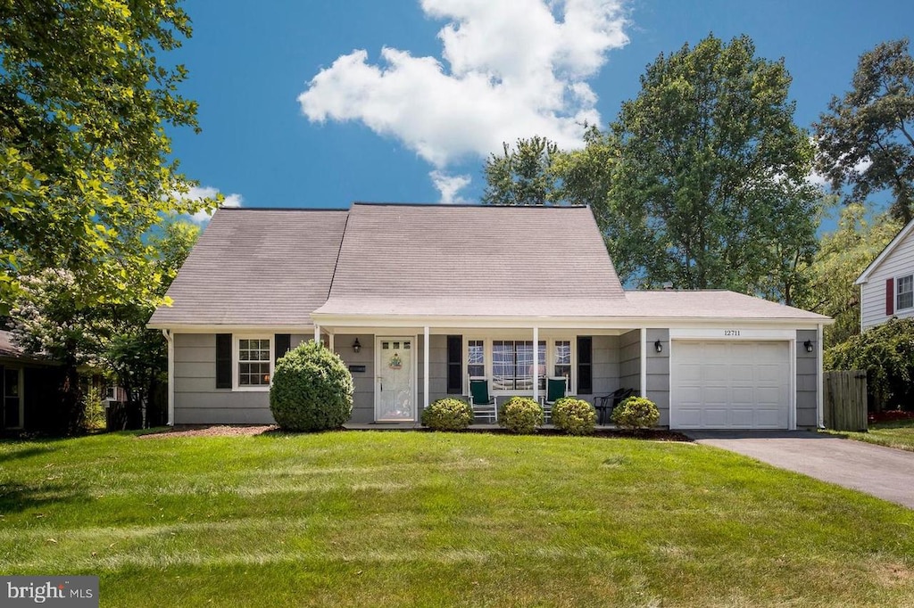 view of front of house featuring a porch, a garage, and a front lawn