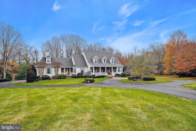 cape cod house featuring covered porch and a front lawn