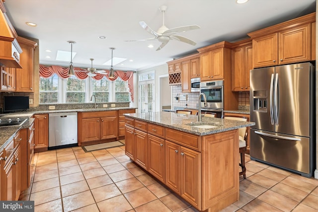 kitchen with sink, backsplash, an island with sink, pendant lighting, and appliances with stainless steel finishes