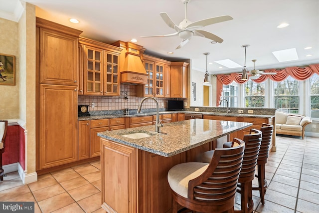 kitchen featuring light stone countertops, backsplash, a skylight, decorative light fixtures, and a breakfast bar area