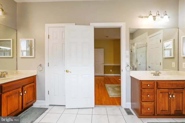 bathroom with a wealth of natural light, tile patterned flooring, vanity, and a shower with door