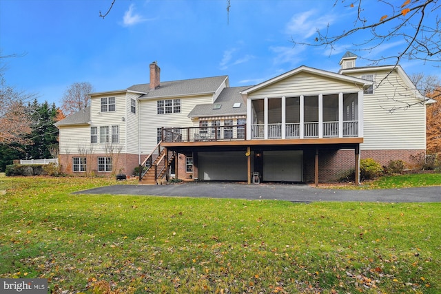 rear view of property featuring a deck, a lawn, and a sunroom