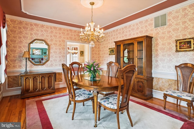 dining space featuring hardwood / wood-style flooring, crown molding, and a chandelier