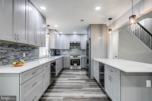 kitchen featuring light wood-type flooring, gray cabinetry, stainless steel appliances, sink, and decorative light fixtures