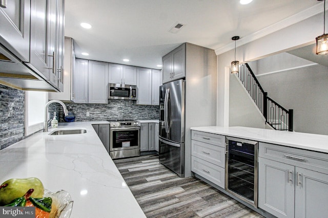 kitchen featuring gray cabinetry, stainless steel appliances, sink, decorative light fixtures, and wine cooler