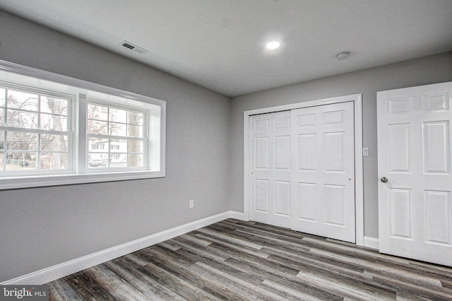 unfurnished bedroom featuring dark hardwood / wood-style floors and a closet