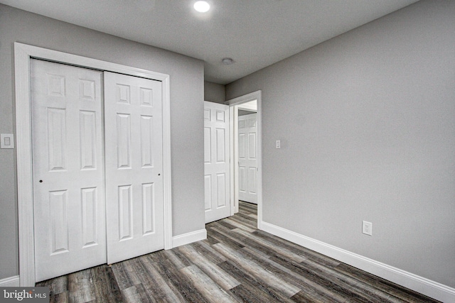 unfurnished bedroom featuring dark wood-type flooring and a closet