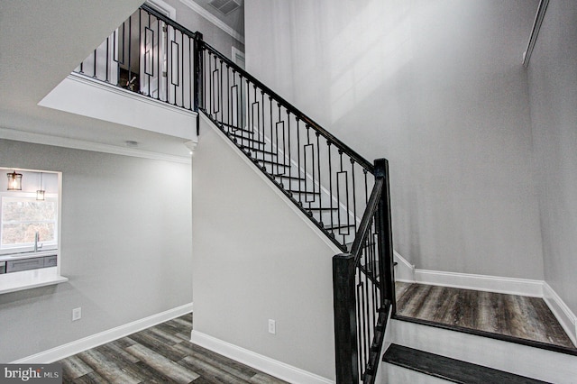 staircase featuring wood-type flooring and crown molding