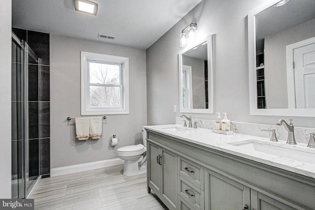 bathroom with vanity, a shower with shower door, and toilet