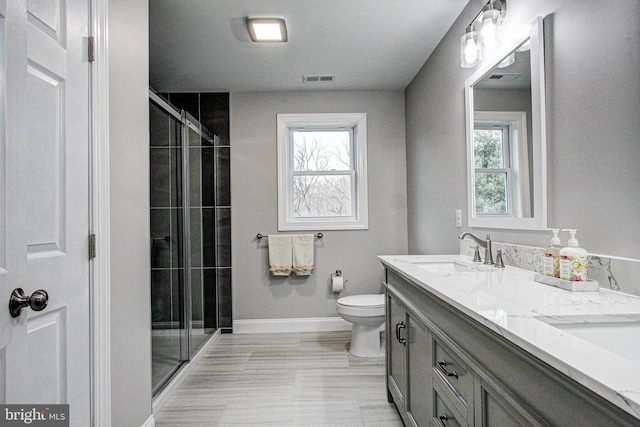 bathroom featuring a wealth of natural light, vanity, a shower with shower door, and toilet