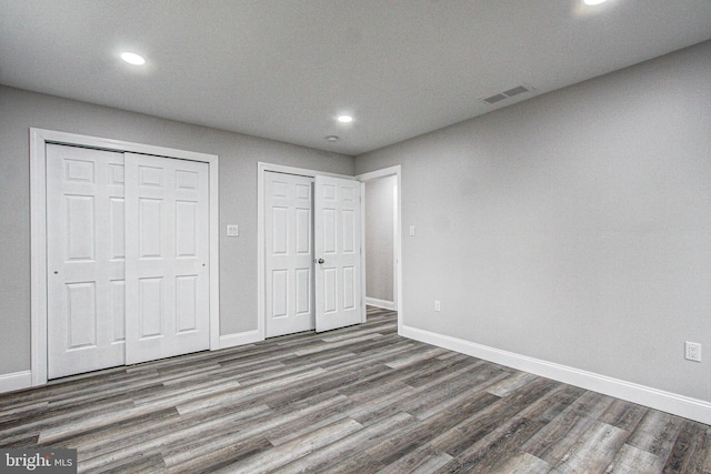 unfurnished bedroom featuring multiple closets and dark hardwood / wood-style floors