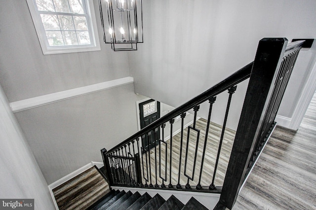 staircase with wood-type flooring and a notable chandelier