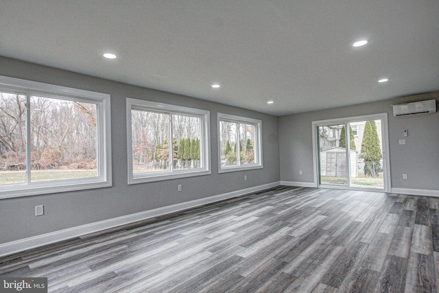 unfurnished room featuring a wall mounted AC and hardwood / wood-style floors