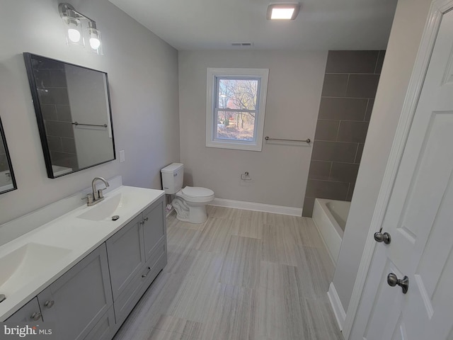 full bathroom featuring hardwood / wood-style flooring, vanity, tiled shower / bath combo, and toilet