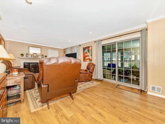 living room featuring a brick fireplace, light hardwood / wood-style flooring, and crown molding