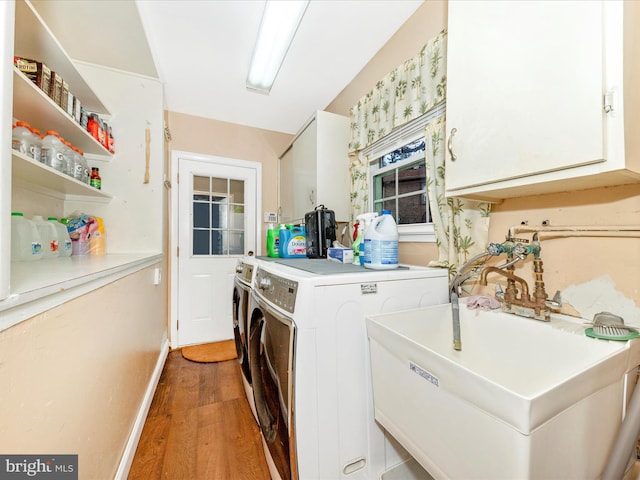 washroom featuring hardwood / wood-style flooring, cabinets, sink, and washing machine and dryer