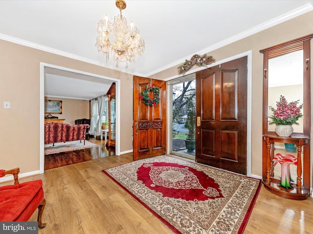 entryway with ornamental molding, a notable chandelier, and hardwood / wood-style flooring