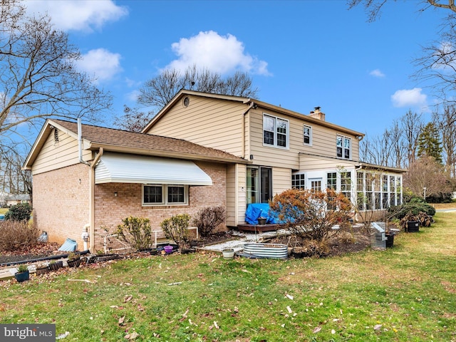 back of house featuring a lawn and a sunroom