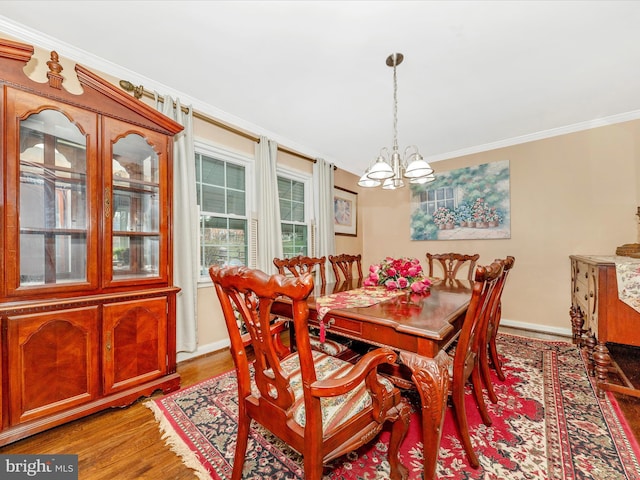 dining area with hardwood / wood-style floors, a notable chandelier, and crown molding