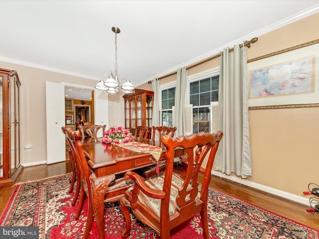 dining space with dark hardwood / wood-style flooring, an inviting chandelier, and ornamental molding