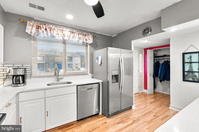 8111 Bird Ln, Greenbelt, MD 20770 - kitchen featuring stainless steel appliances, white cabinets, light countertops, light wood-style floors, and a ceiling fan