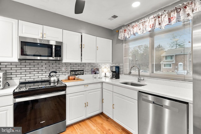 8111 Bird Ln, Greenbelt, MD 20770 - kitchen with stainless steel appliances, light countertops, white cabinets, decorative backsplash, and light wood-style flooring