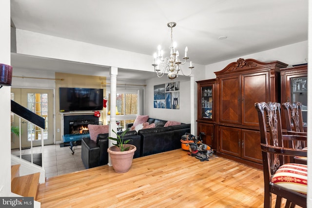 8111 Bird Ln, Greenbelt, MD 20770 - living room featuring a chandelier, a warm lit fireplace, wood finished floors, and stairs