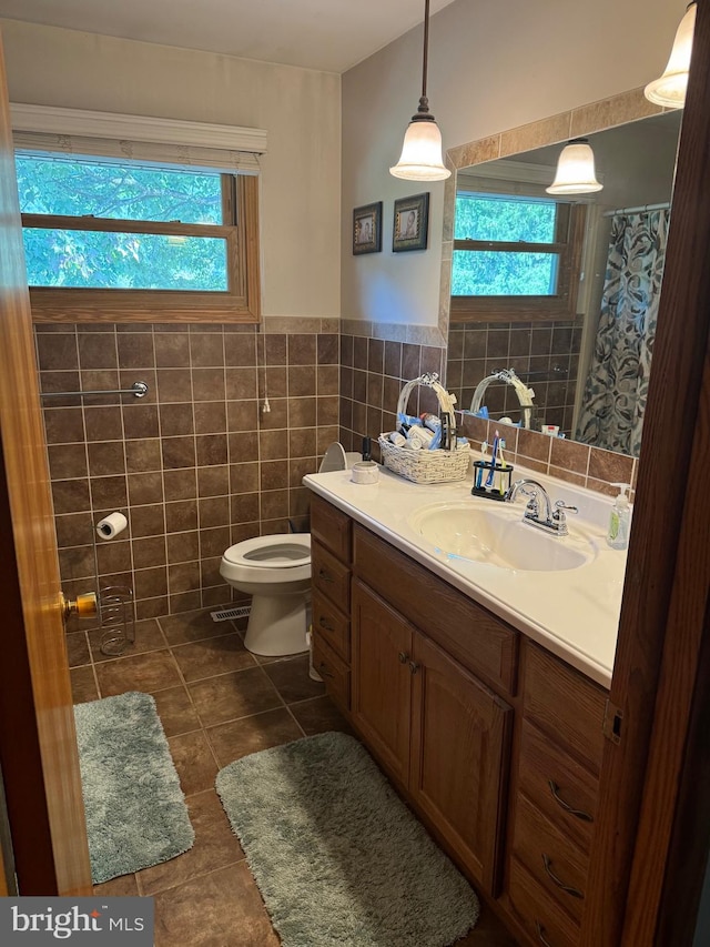 bathroom with tile patterned floors, plenty of natural light, tile walls, and vanity