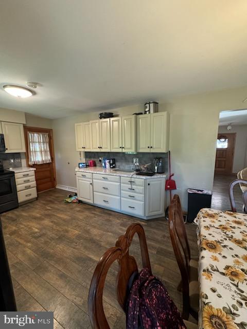 kitchen featuring white cabinets, black electric range oven, dark hardwood / wood-style flooring, and backsplash