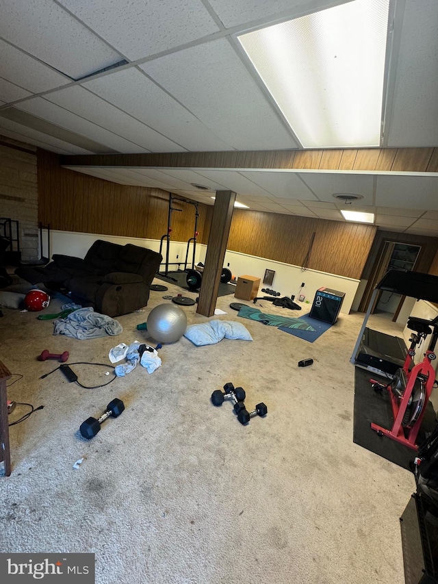 basement with carpet, a paneled ceiling, and wood walls