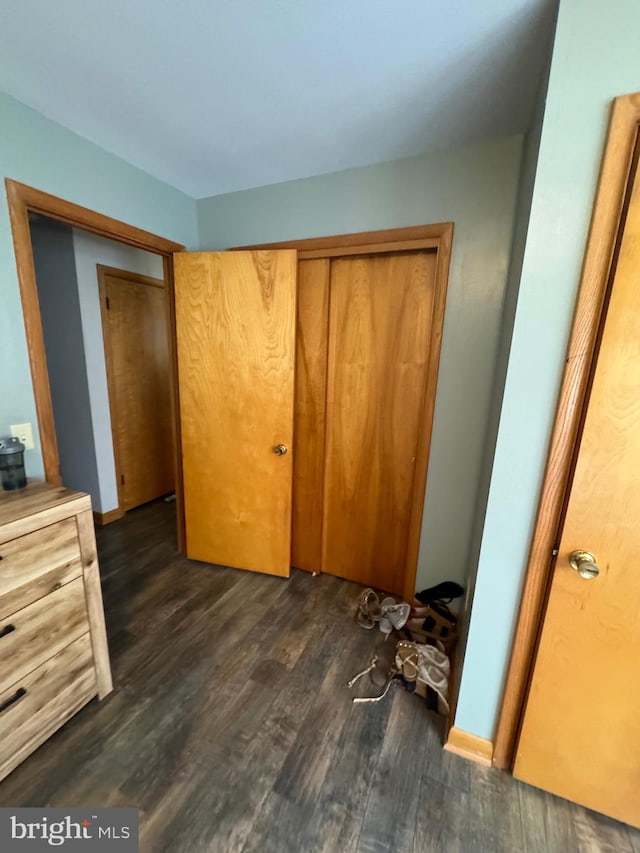 unfurnished bedroom with dark hardwood / wood-style flooring and a closet